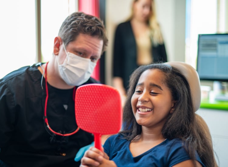 Child smiling in a dentist's chair at Kaleidoscope Kids Dentistry in Midvale, UT