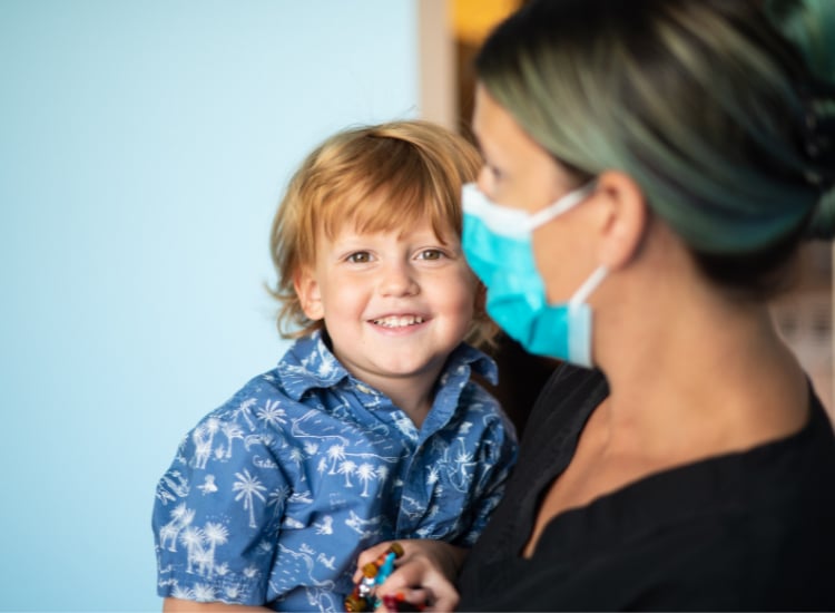 Pediatric dentist examining a young patient’s teeth with a friendly smile